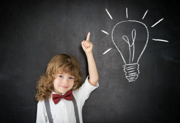 Smart kid in class. Happy child against blackboard. Drawing light bulb. Idea concept